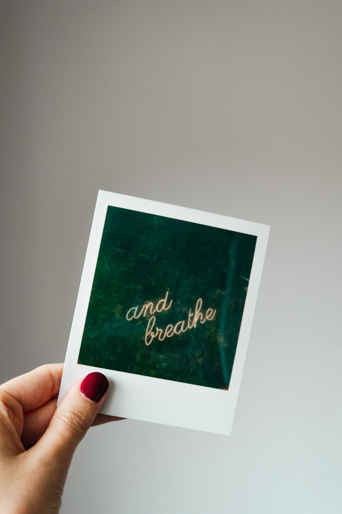 Polaroid photo with a green background and the words "and breathe" on it. If you are feeling overwhelmed with anxiety, an online therapist for anxiety in north carolina can help. Learn more here.
