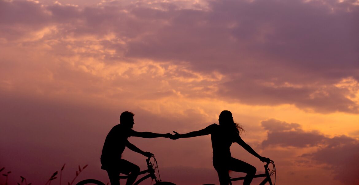 two people on bikes holding hands. attachment trauma, relationship trauma, online counseling for relationship issues in NC