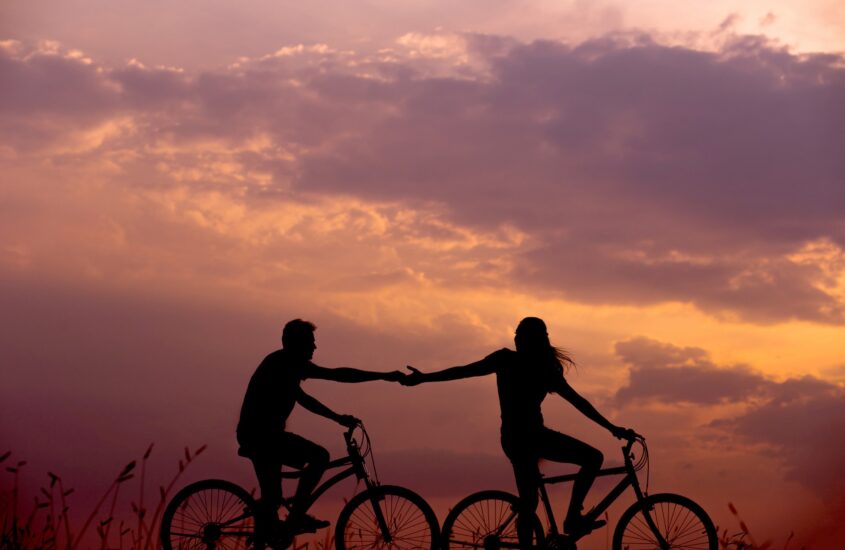 two people on bikes holding hands. attachment trauma, relationship trauma, online counseling for relationship issues in NC