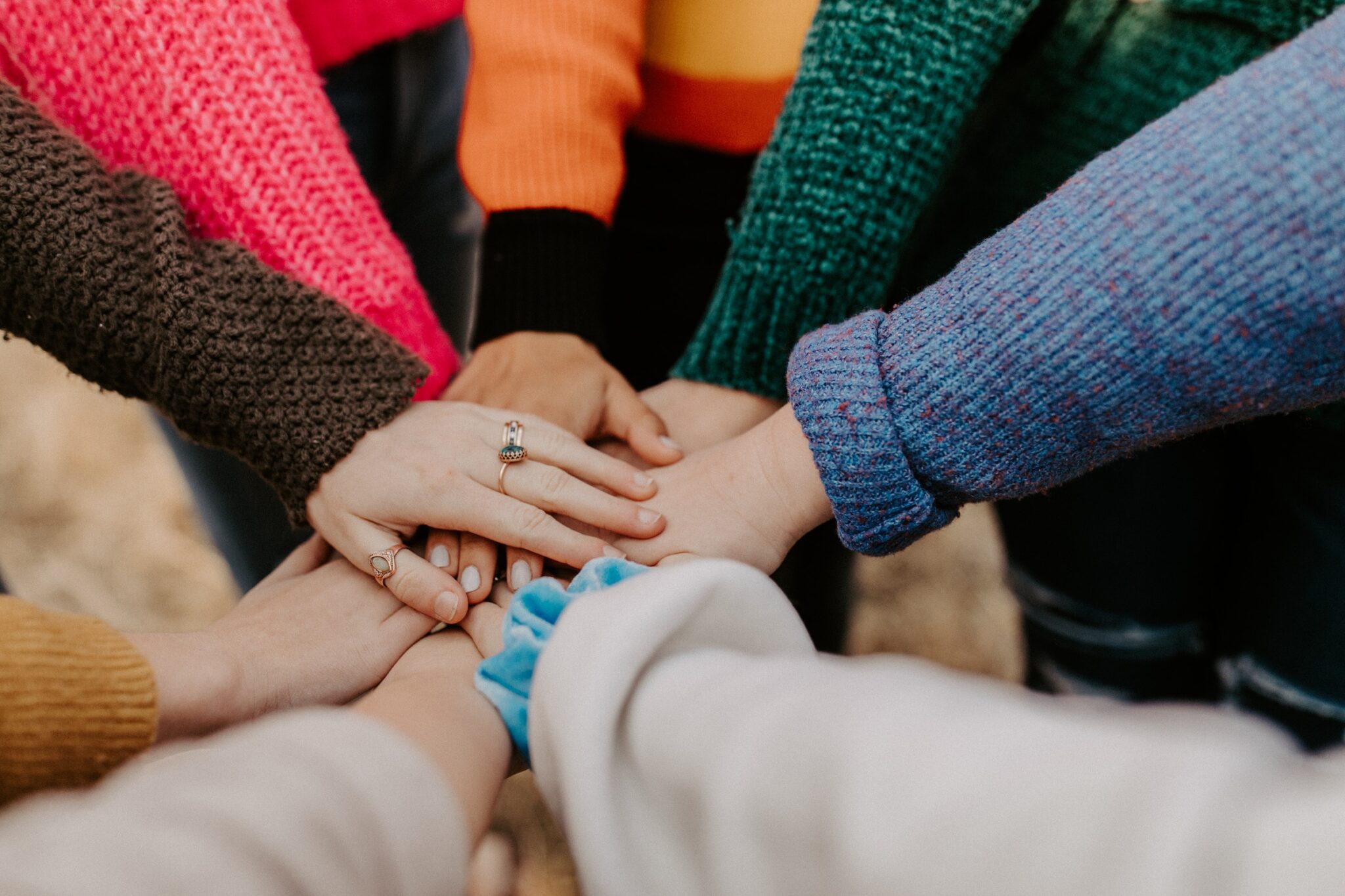 Group of friends standing in a circle holding hands supporting each other. North carolina postpartum therapist. Care for postpartum depression.