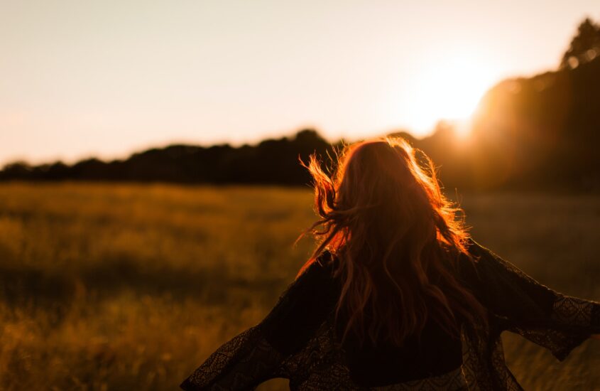 Woman running in open field with arms outstretched at sunset. Heal from your trauma. EMDR therapy.