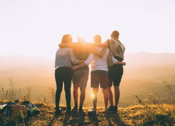 A group of friends standing on a hill, silhouetted against a setting sun. Symbolic image representing Group Therapy.