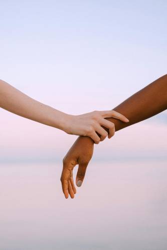 Two individuals holding hands over the water, symbolizing unity and support during a counseling in Davidson NC.