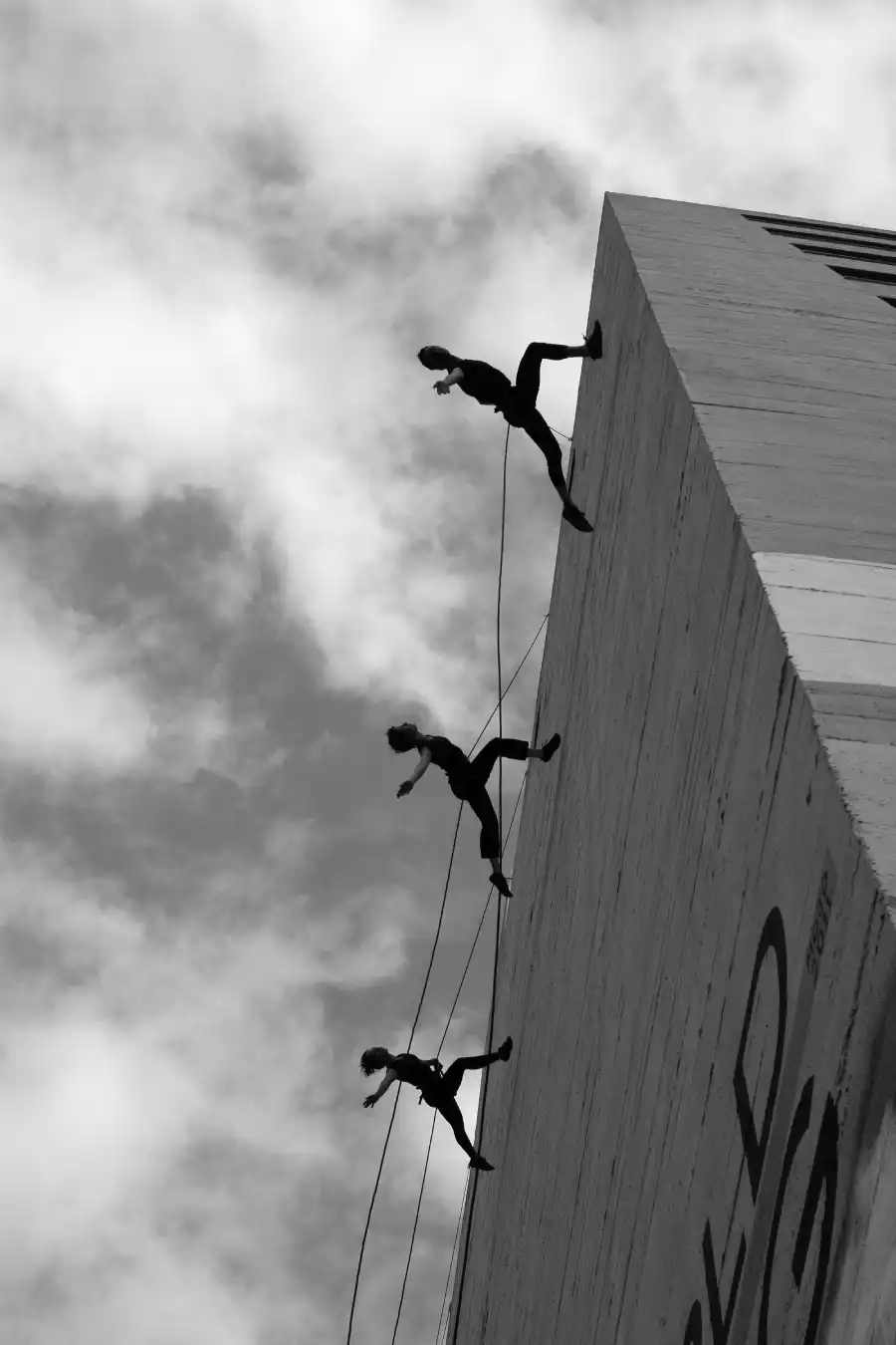 A group of people defying perfectionism, climbing a building with resilience and unity.